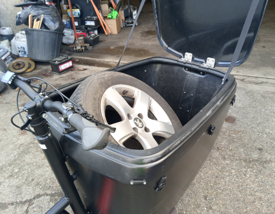 Une roue de voiture dans la caisse d'un vélo-cargo